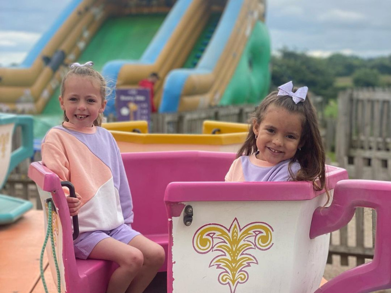 Children's Tea cup ride with a bouncy castle slide in the back ground