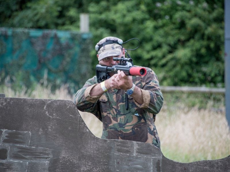 Laser combat player dressed in camouflage with the light sensor on his hat