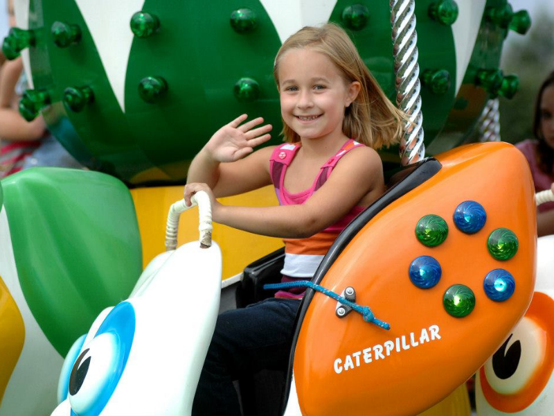 Funfair ride with a smiling waving girl on it.